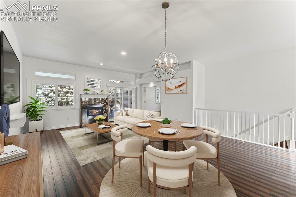 Image 9 of 50: Virtually staged dining room with a premium fireplace, dark wood-style floo