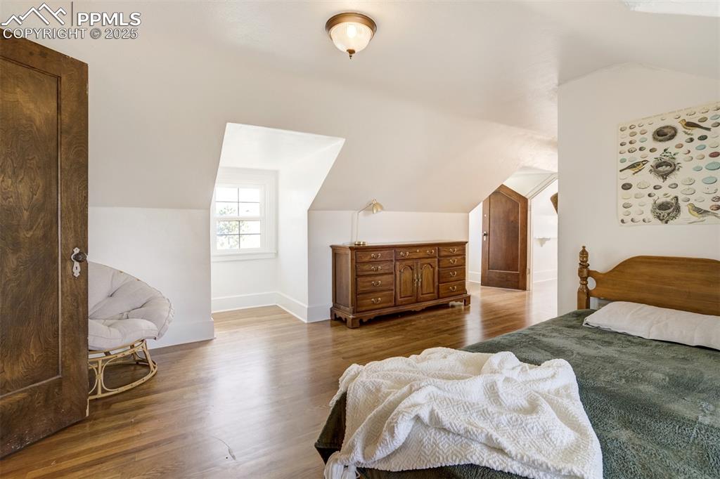 Image 32 of 50: 3rd bedroom featuring lofted ceiling, wood finished floors, and baseboards