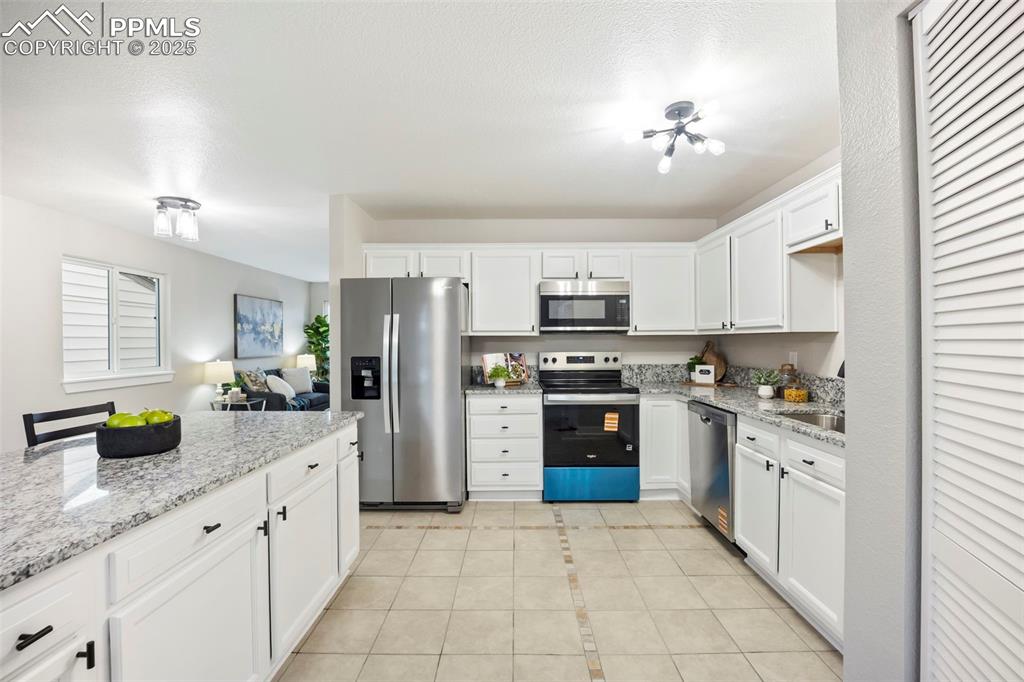 Image 11 of 33: Kitchen featuring white cabinetry, appliances with stainless steel finishes