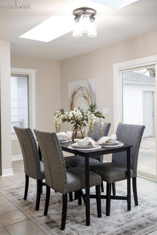 Image 15 of 33: Dining room with light tile patterned floors, a skylight, and a textured ce