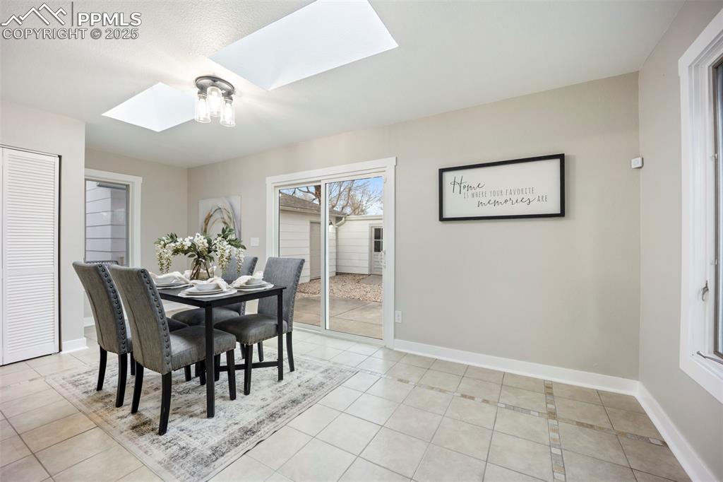 Image 17 of 33: Dining area with a skylight and light tile patterned floors