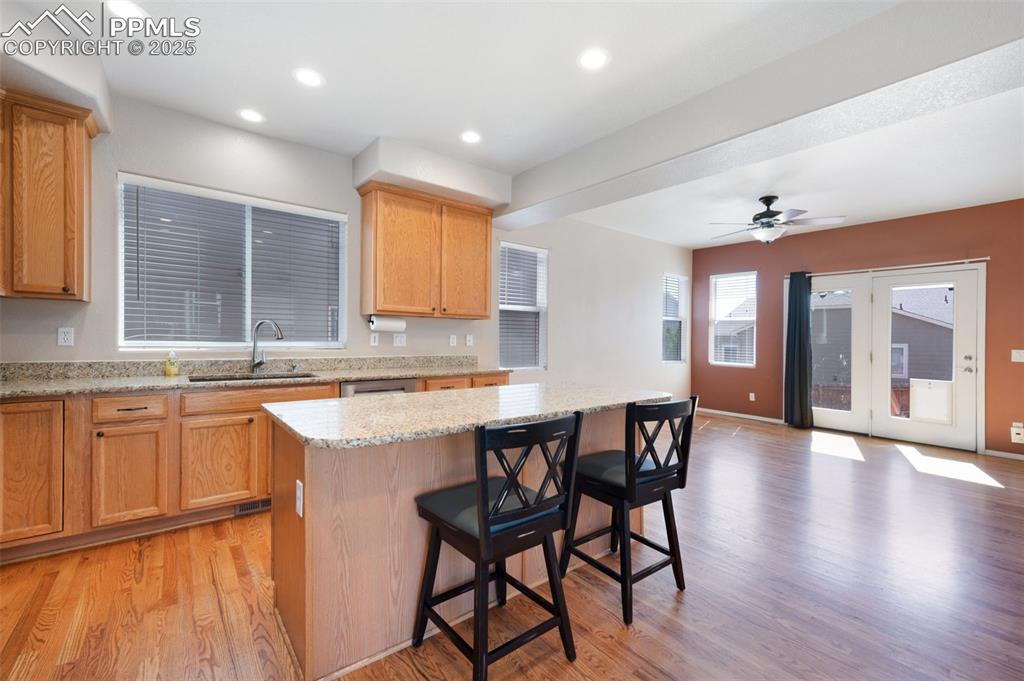 Image 14 of 46: Kitchen with stainless steel appliances, light stone counters, light wood f