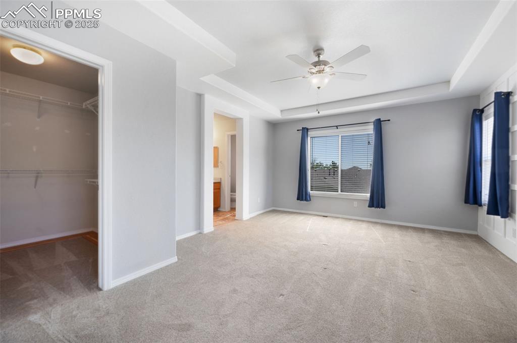 Image 24 of 46: Spare room with a tray ceiling, a ceiling fan, and light colored carpet