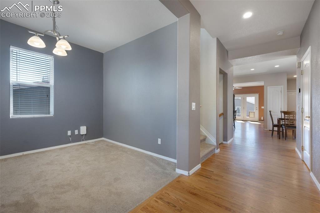 Image 6 of 46: Empty room with light wood-style flooring, a chandelier, stairway, and ligh