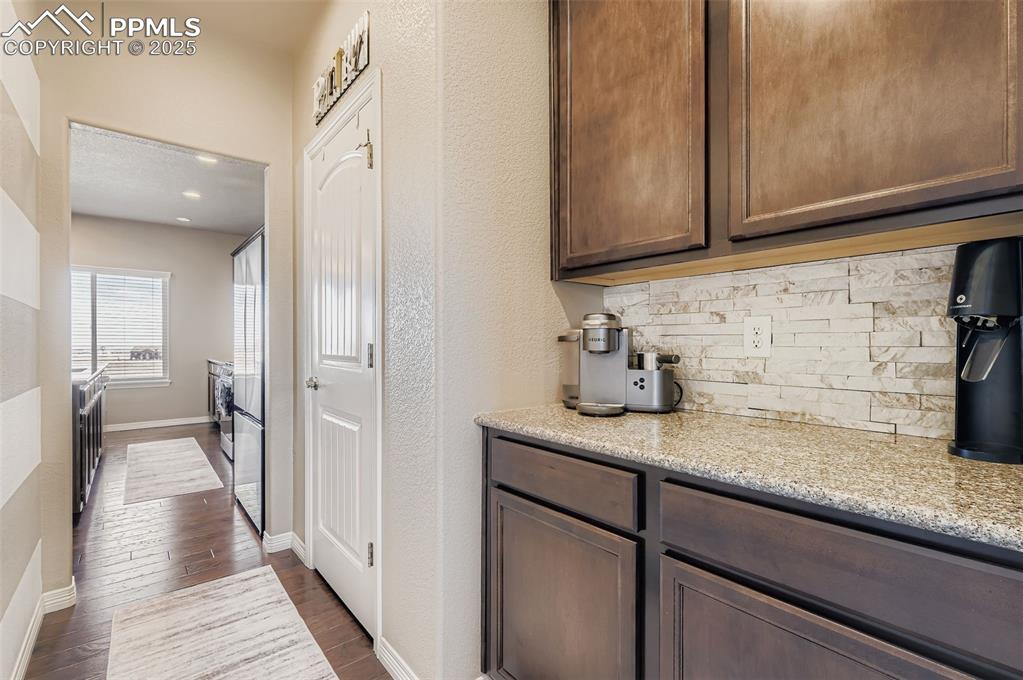 Image 11 of 35: Kitchen with light stone countertops, dark wood-style flooring, tasteful ba
