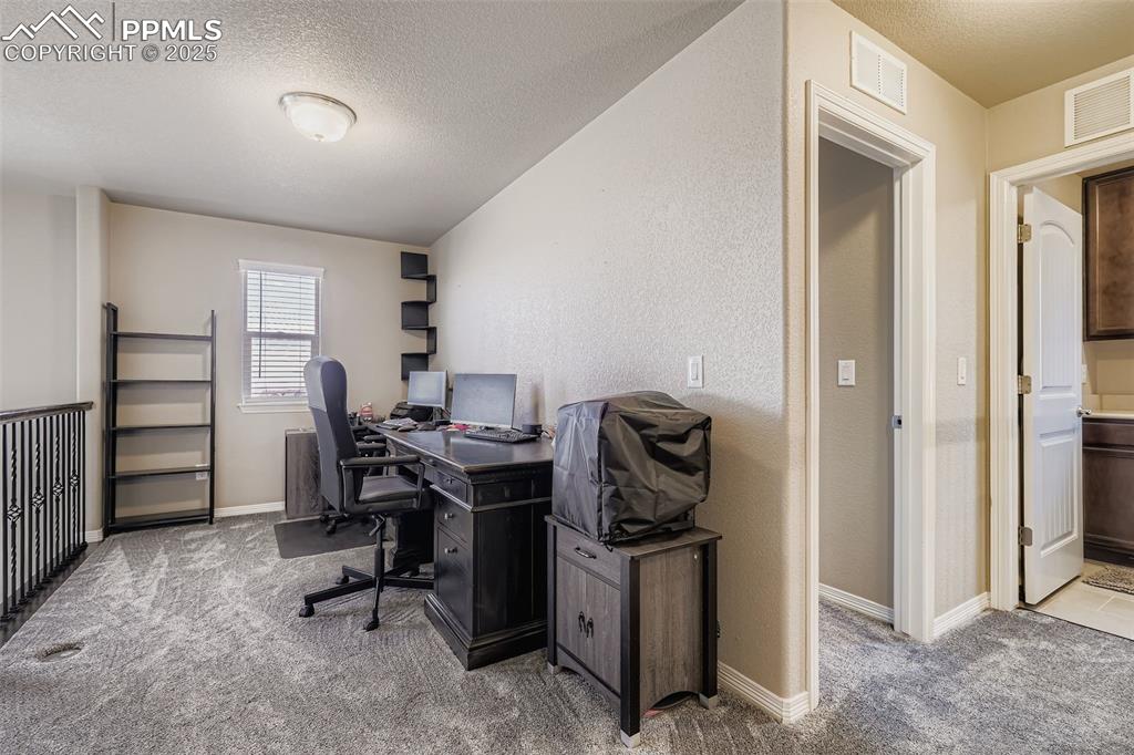Image 21 of 35: Office featuring a textured ceiling, light carpet, and a textured wall