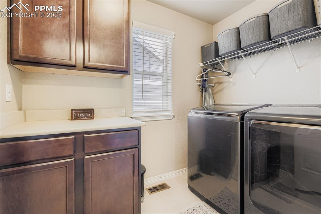 Image 22 of 35: Laundry area with cabinet space, light tile patterned flooring, and washing