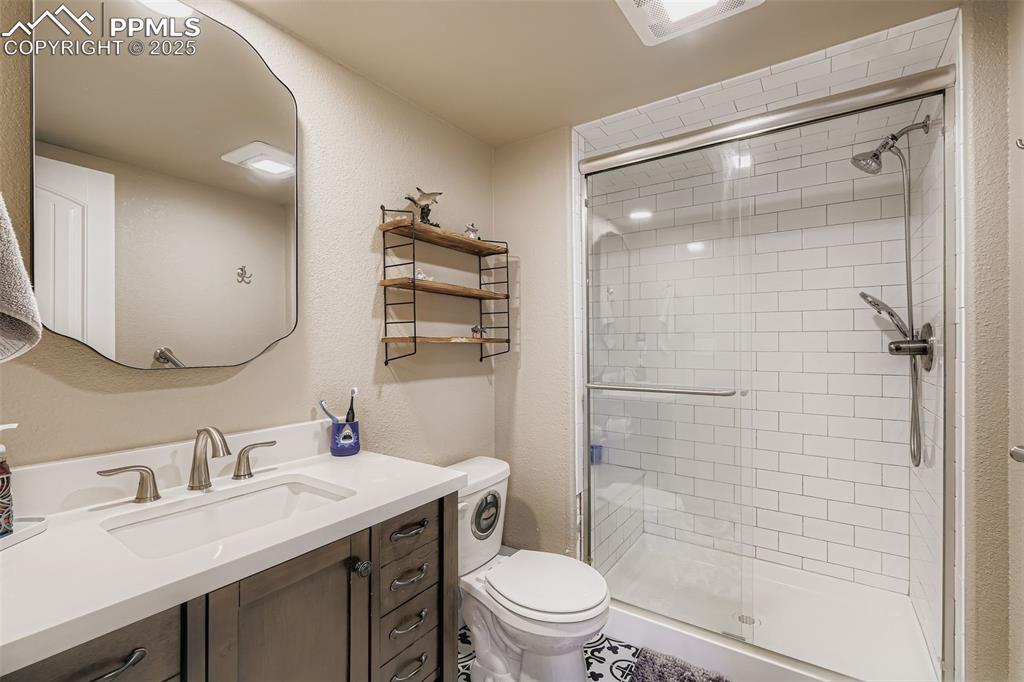 Image 24 of 35: Bathroom with a textured wall, vanity, and a shower stall