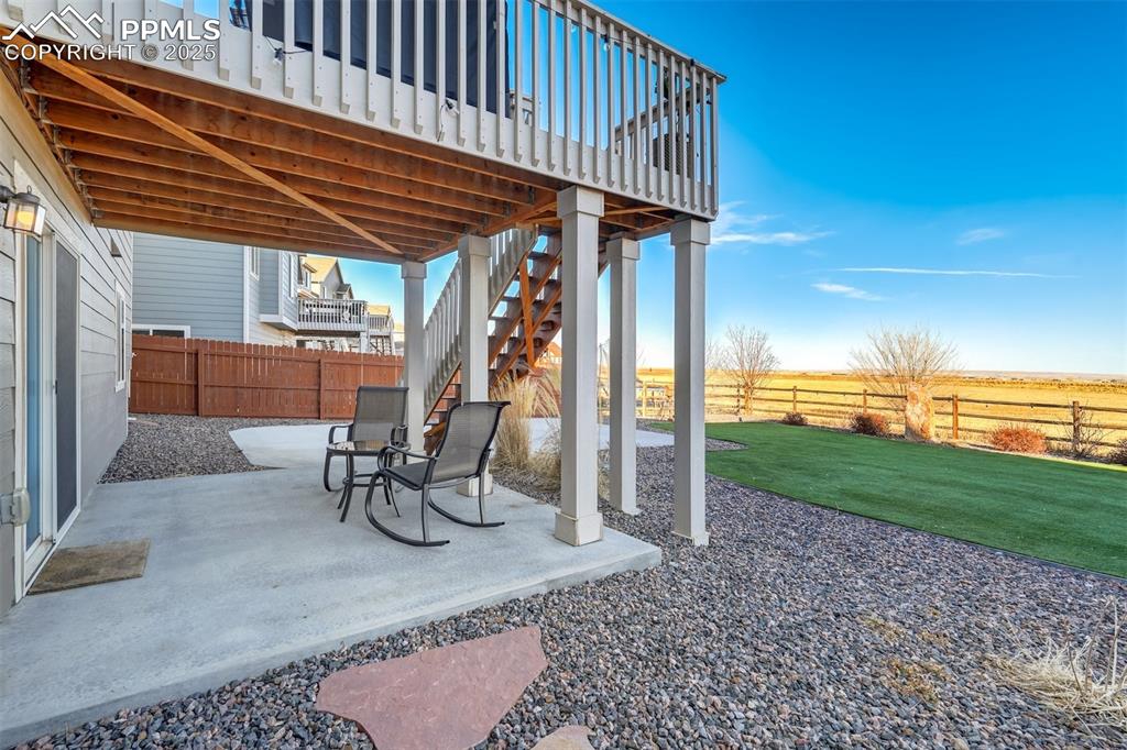 Image 28 of 35: Fenced backyard with a patio, a wooden deck, stairway, and a view of rural 
