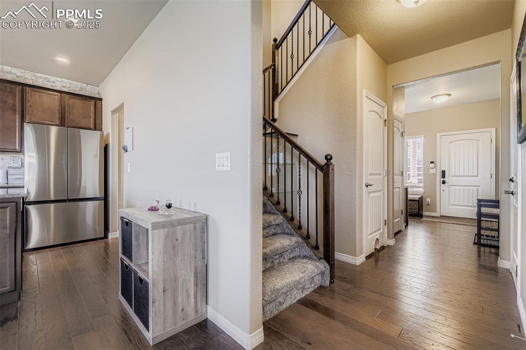 Image 4 of 35: Kitchen with dark wood-style floors, freestanding refrigerator, and dark br