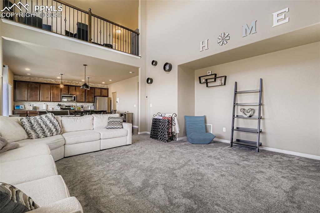 Image 5 of 35: Living area with carpet and a high ceiling