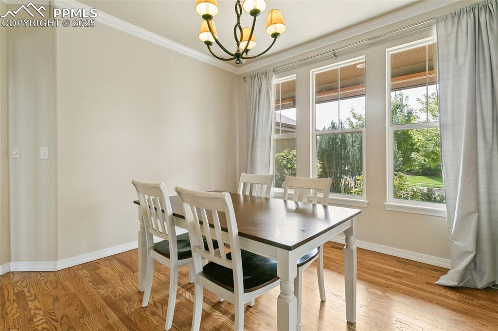 Image 10 of 37: Dining area with ornamental molding, a chandelier, and light wood-style flo