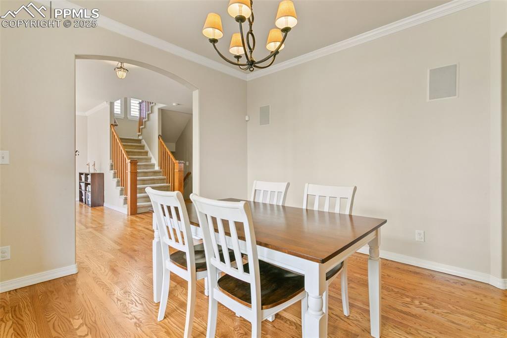 Image 11 of 37: Dining room with crown molding, light wood finished floors, arched walkways