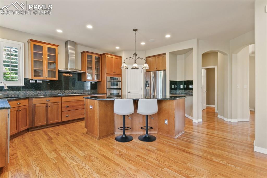 Image 12 of 37: Kitchen featuring backsplash, glass insert cabinets, a breakfast bar, a kit