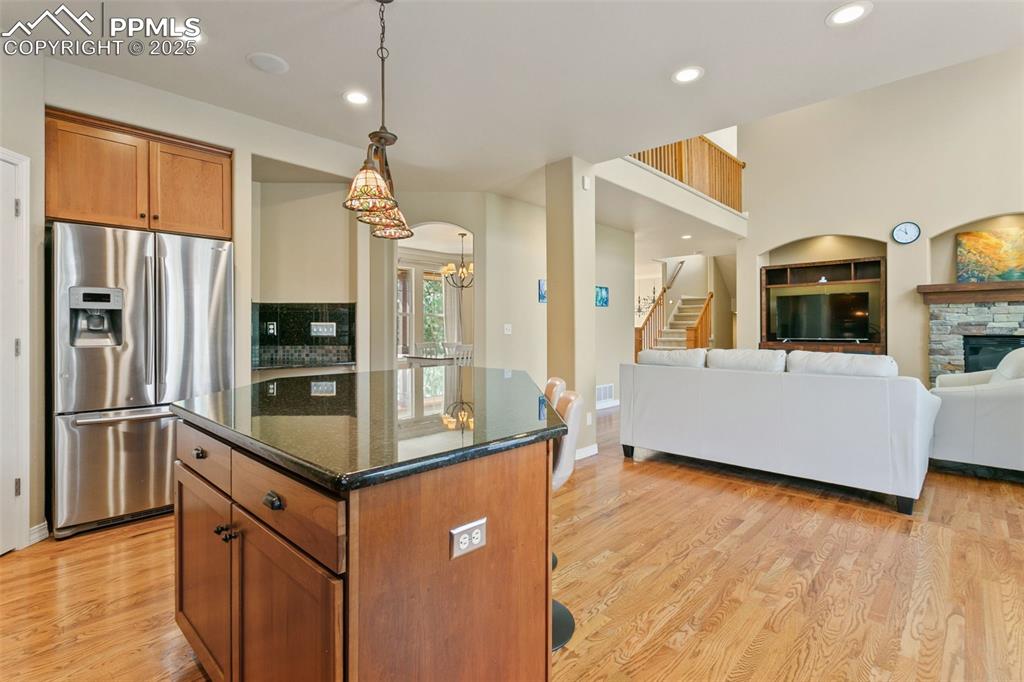 Image 13 of 37: Kitchen featuring brown cabinetry, dark stone countertops, stainless steel