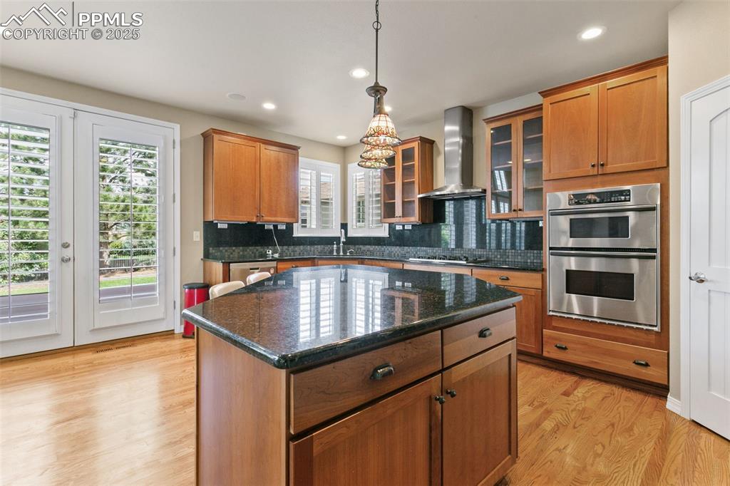 Image 15 of 37: Kitchen featuring dark stone countertops, light wood-type flooring, a kitch