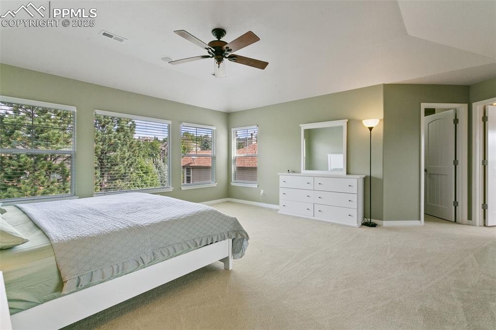 Image 18 of 37: Bedroom featuring light colored carpet, vaulted ceiling, and a ceiling fan