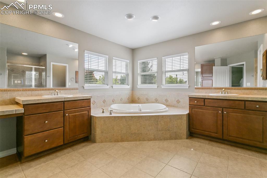 Image 21 of 37: Bathroom with a shower stall, two vanities, light tile patterned floors, a
