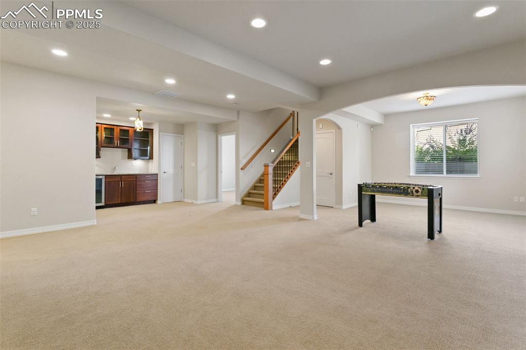 Image 28 of 37: Rec room featuring recessed lighting, light carpet, arched walkways, wet ba