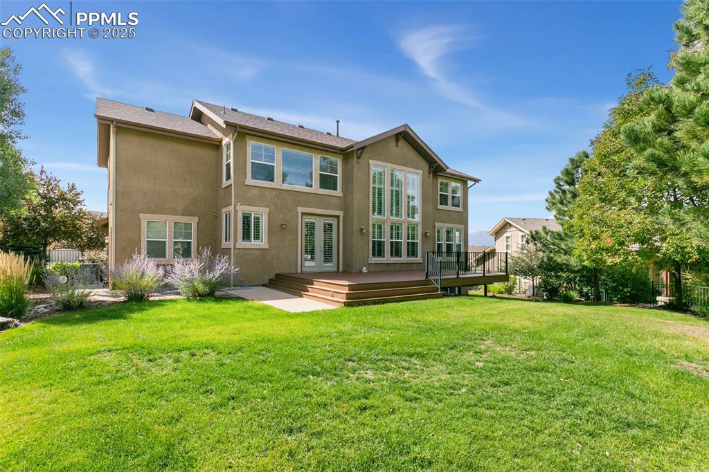 Image 37 of 37: Rear view of house with stucco siding and a wooden deck
