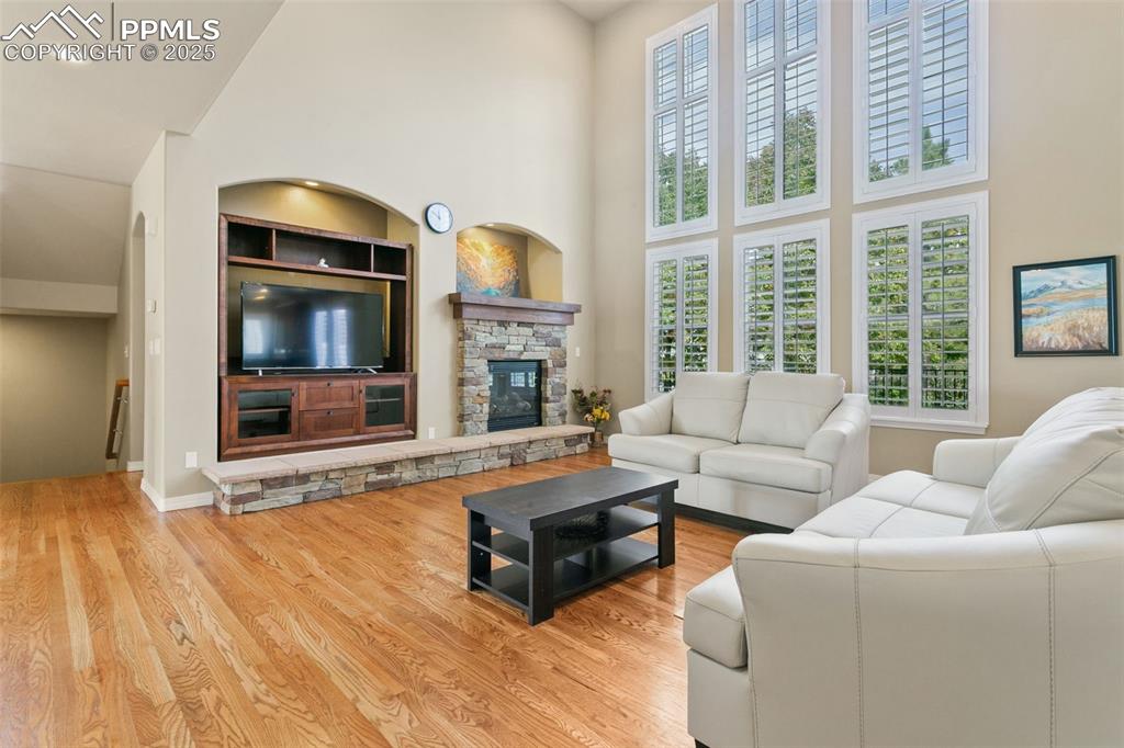 Image 4 of 37: Living area with built in shelves, a towering ceiling, wood finished floors