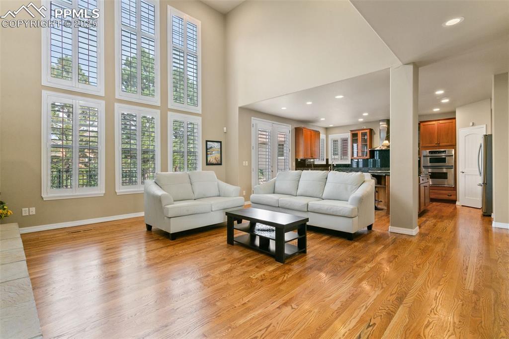 Image 5 of 37: Living area with plenty of natural light, light wood-style floors, a high c