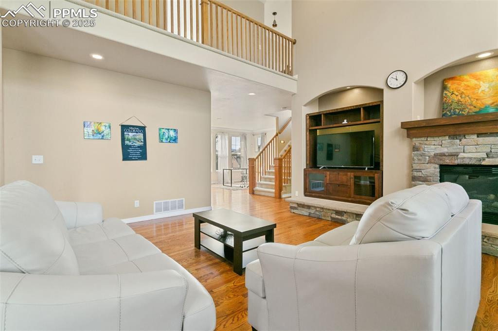 Image 7 of 37: Living room with wood finished floors, stairway, a high ceiling, recessed l