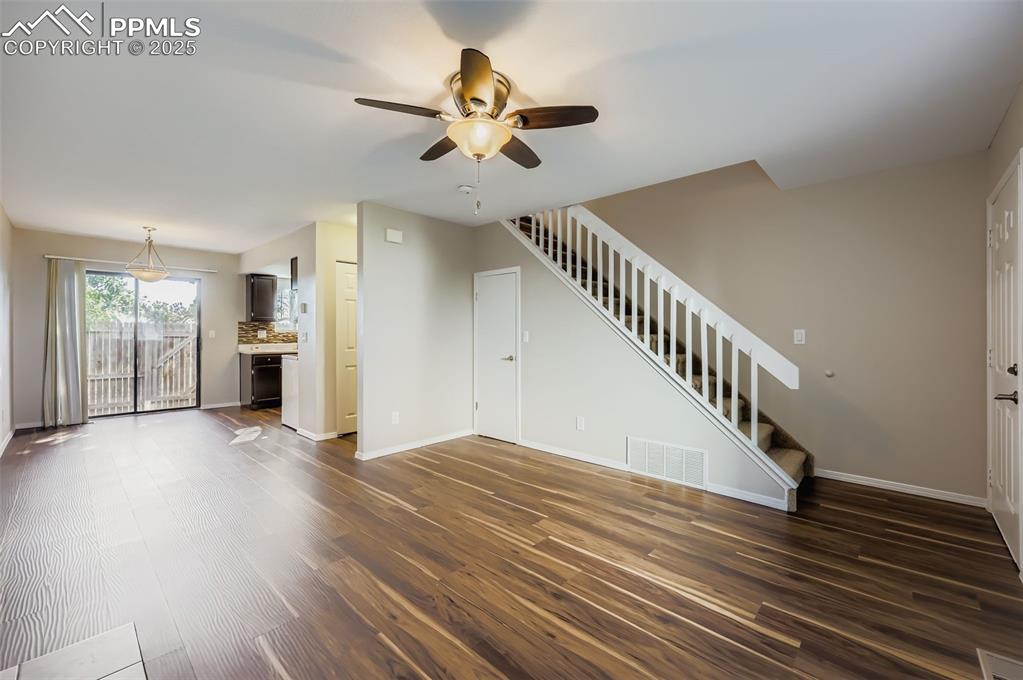 Image 7 of 24: Unfurnished living room featuring stairs, dark wood-type flooring, and a ce