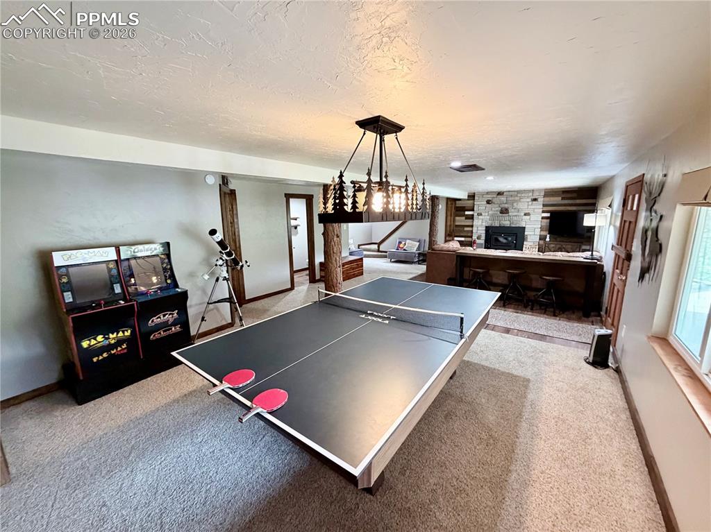 Image 13 of 20: Playroom featuring a fireplace, a textured ceiling, and light carpet