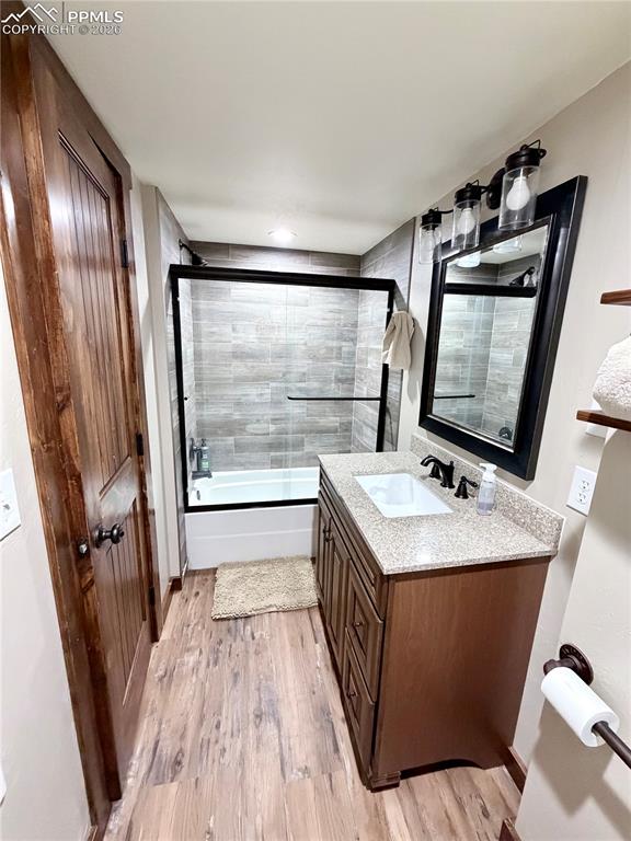 Image 14 of 20: Bathroom with bath / shower combo with glass door, vanity, and light wood-s