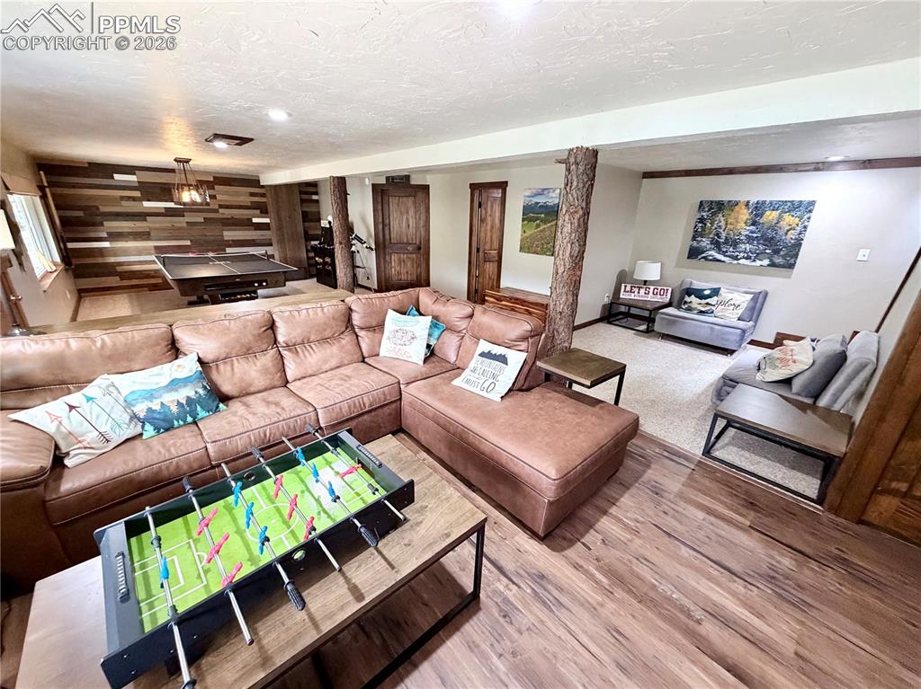 Image 15 of 20: Living area featuring wood finished floors, wood walls, and a textured ceil