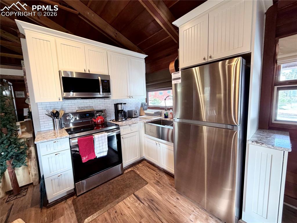 Image 4 of 20: Kitchen with stainless steel appliances, light stone countertops, wood ceil
