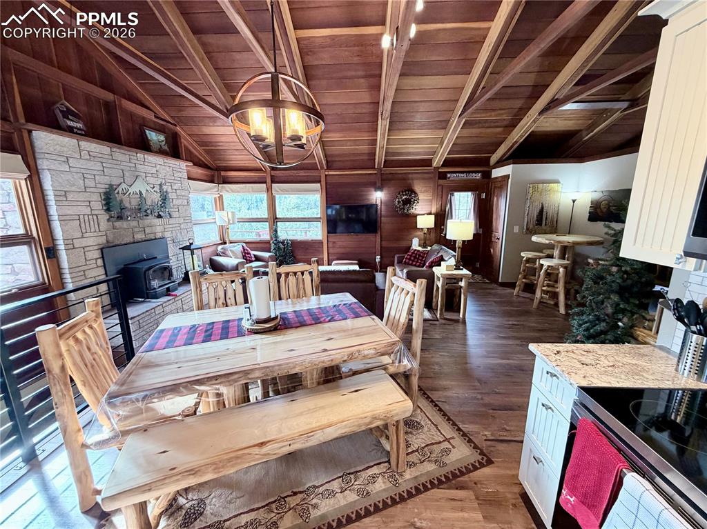 Image 5 of 20: Dining space featuring dark wood finished floors, a wood stove, wood walls,