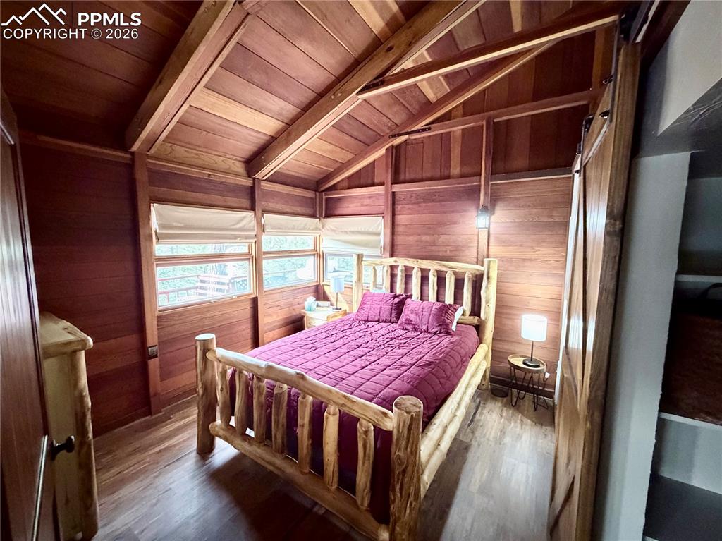 Image 7 of 20: Bedroom featuring wood finished floors, wood walls, and wooden ceiling