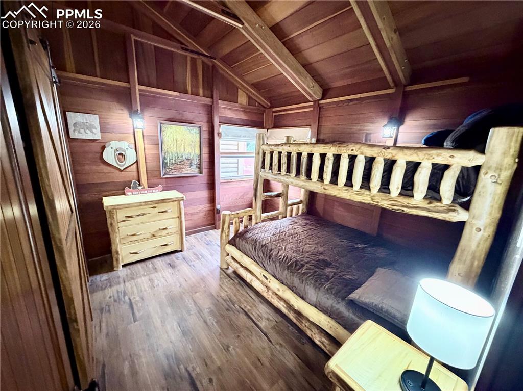 Image 8 of 20: Bedroom with hardwood / wood-style flooring, wooden walls, and wood ceiling