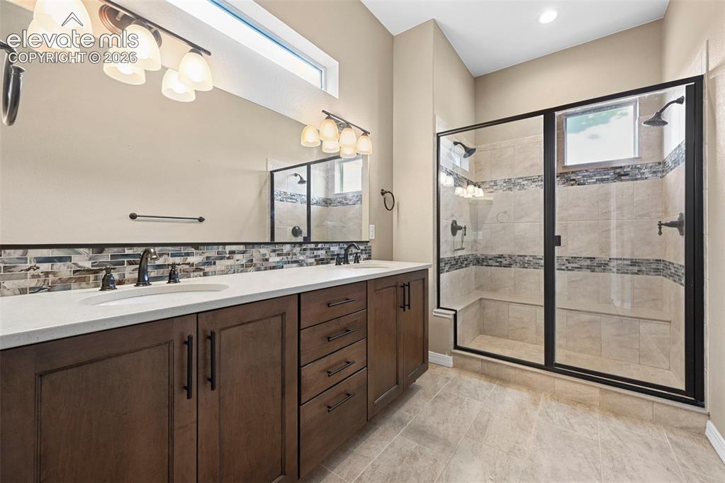 Image 11 of 37: Spacious bathroom featuring a dual vanity with a white countertop and wood-