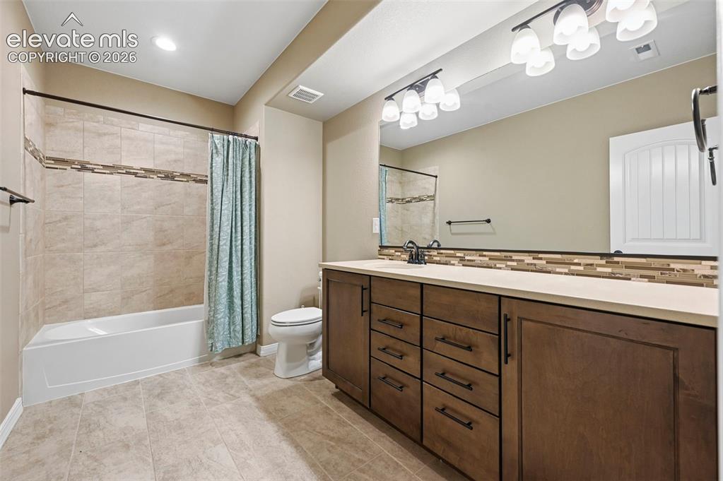 Image 19 of 37: Bathroom featuring an expansive vanity with rich wood-finish cabinetry, a l