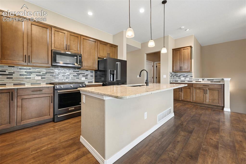 Image 4 of 37: Kitchen featuring wood-finish flooring, an oversized island with pendant li