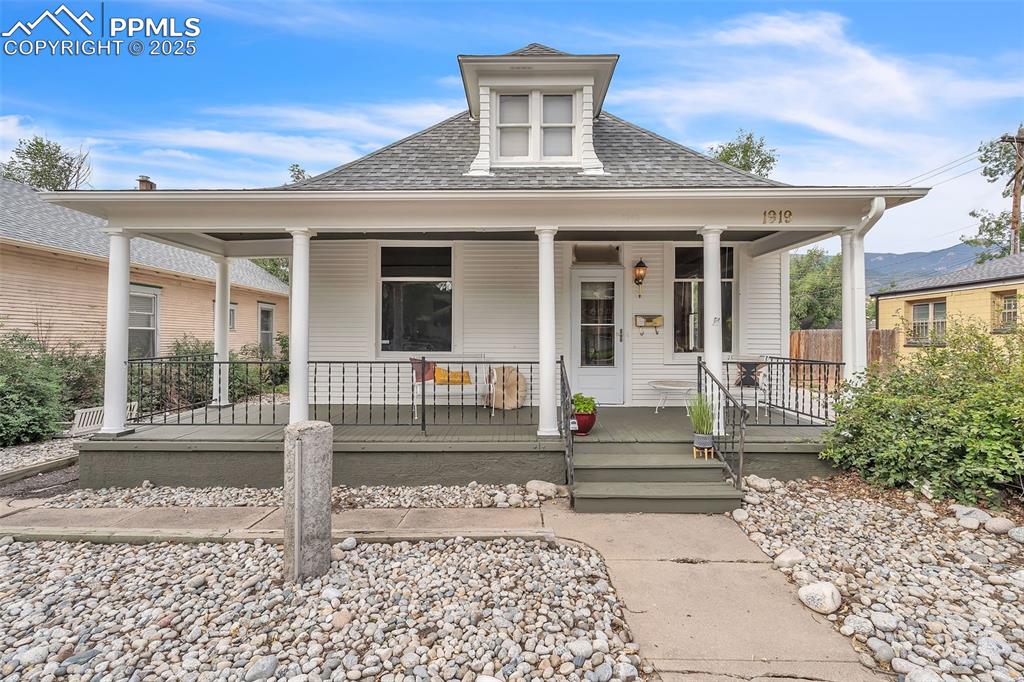 Caption: View of front facade featuring roof with shingles and a porch