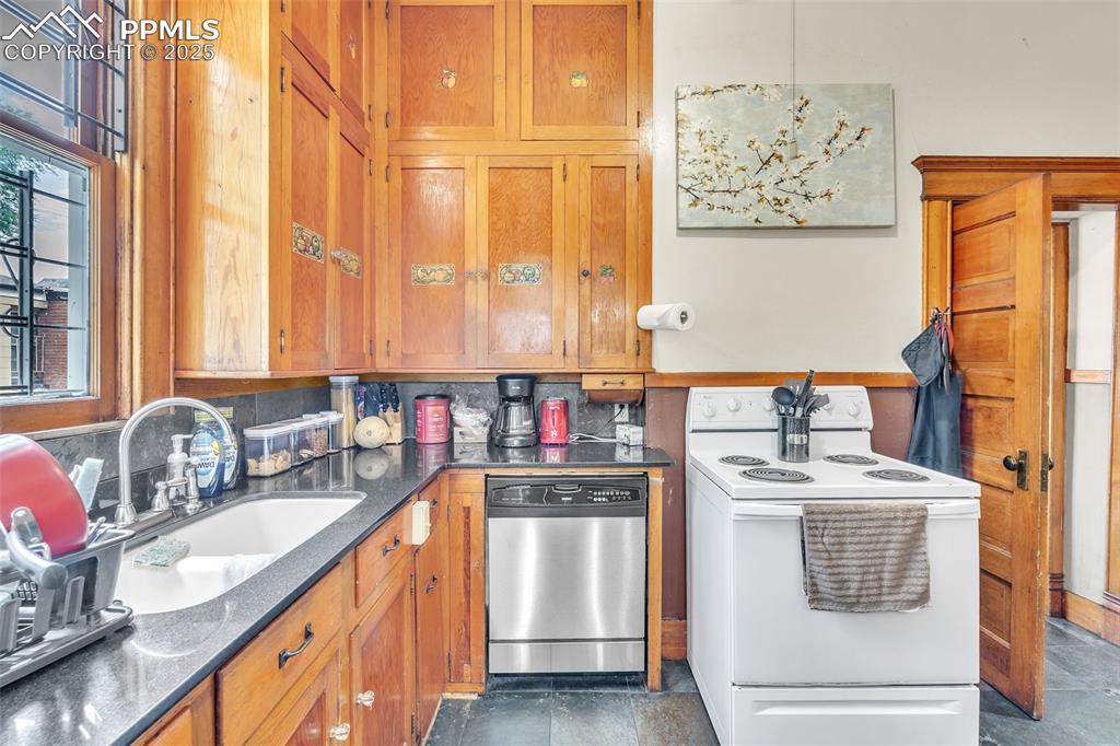 Image 17 of 49: Kitchen with white range with electric cooktop, dishwasher, brown cabinets,