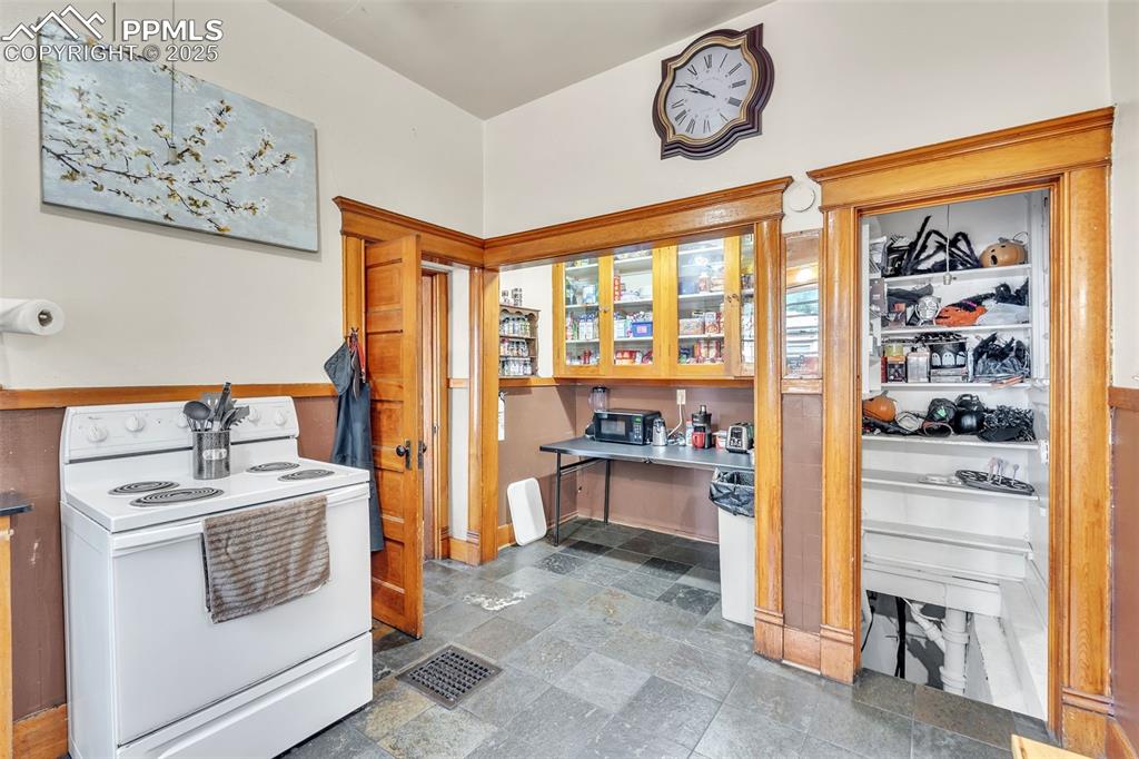 Image 18 of 49: Kitchen featuring white electric range, stone tile floors, and built in stu