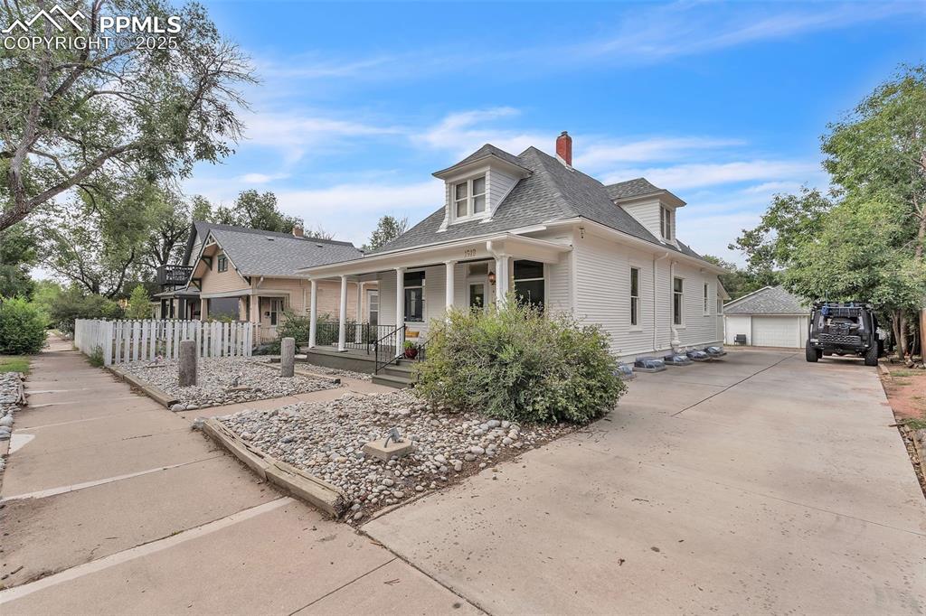 Image 2 of 49: Bungalow-style house with an outbuilding, a chimney, a detached garage, roo