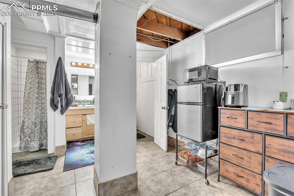 Image 24 of 49: Kitchen with light tile patterned floors, black microwave, and freestanding