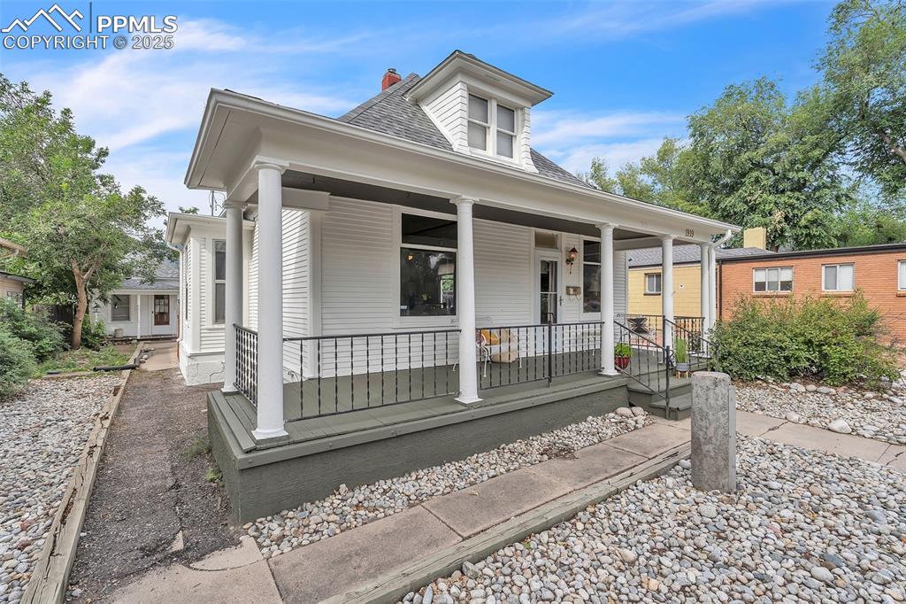 Image 3 of 49: View of front of property featuring roof with shingles, a chimney, and a po