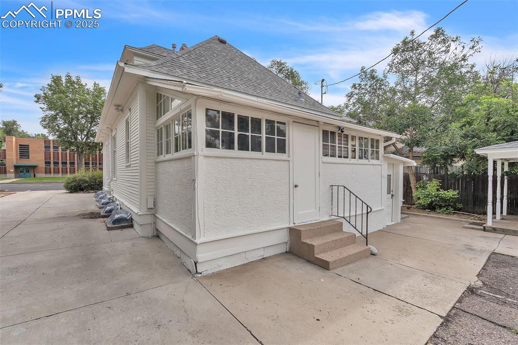 Image 37 of 49: View of side of property with a shingled roof, a patio, entry steps, and st