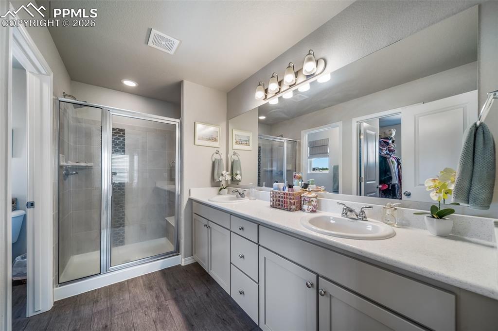 Image 12 of 45: Primary bathroom with dual vanities, quartz countertops, and walk in closet