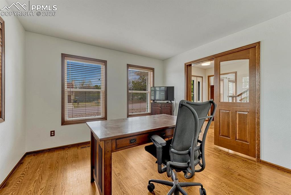 Image 11 of 44: Interior room featuring wood-finish flooring, white walls, and three window
