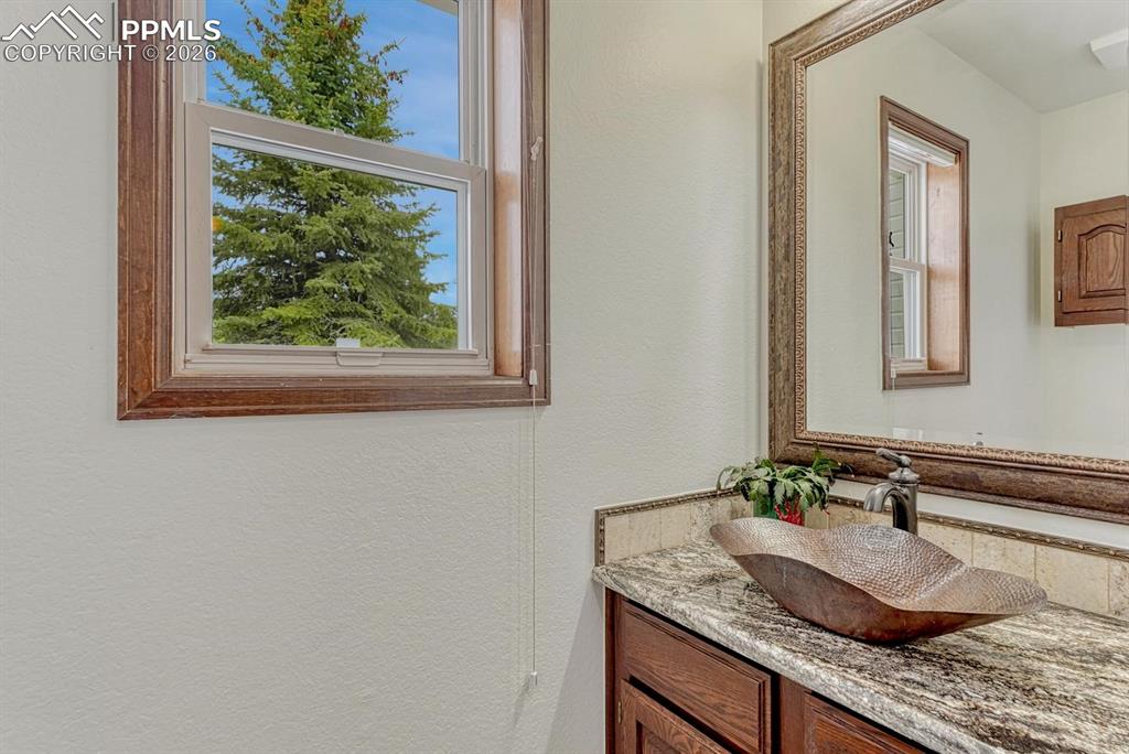 Image 21 of 44: Bathroom featuring a unique vessel sink, granite-style countertop, and wood