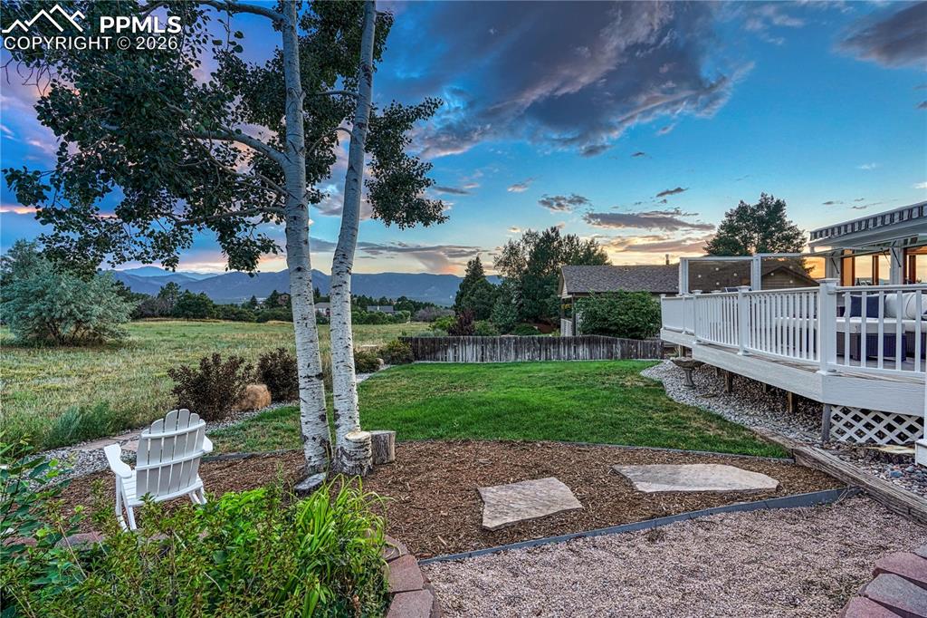 Image 25 of 44: Expansive backyard featuring a manicured lawn, established trees, and natur