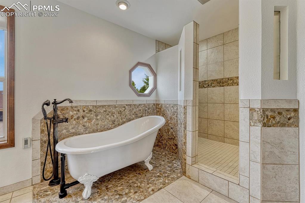 Image 30 of 44: Freestanding soaking tub with floor-mounted faucet, pebble-tile flooring, w